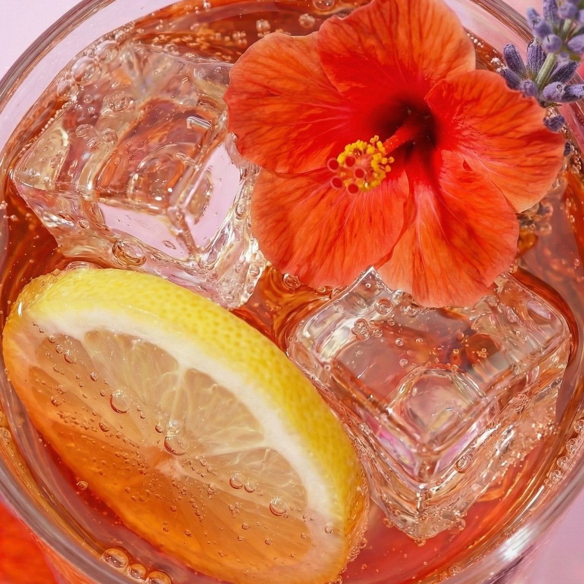Glass of iced tea with lemon slice, red flower, and ice cubes.