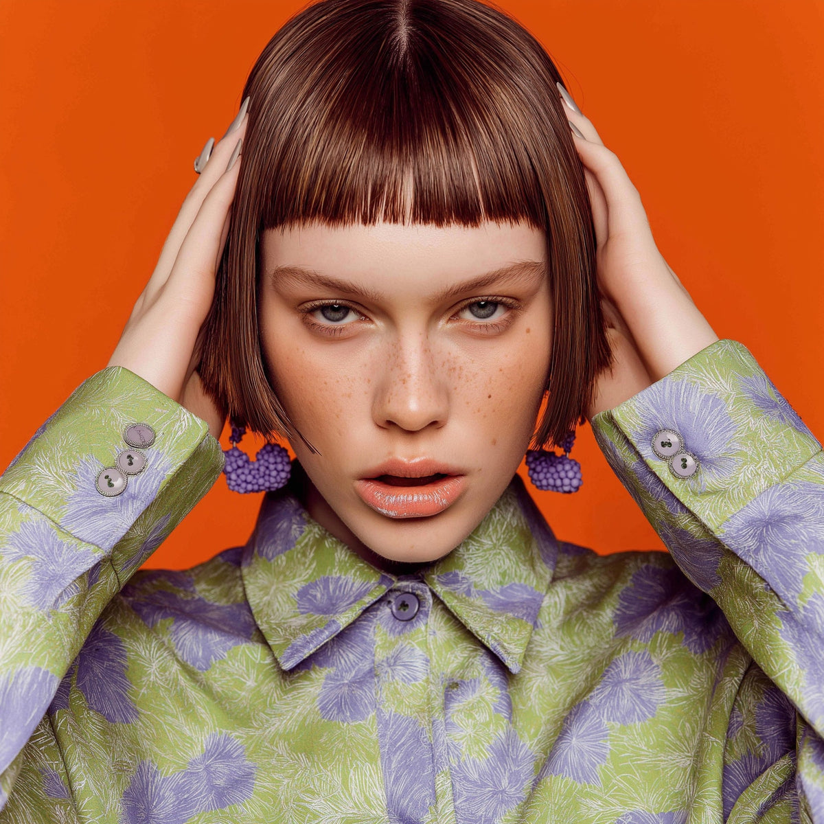 Woman wearing a green and purple patterned coat against an orange background