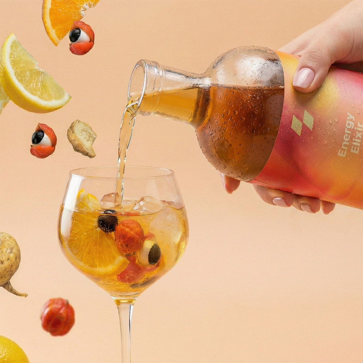 Hand pouring a drink from a bottle into a glass with fruit on a peach background
