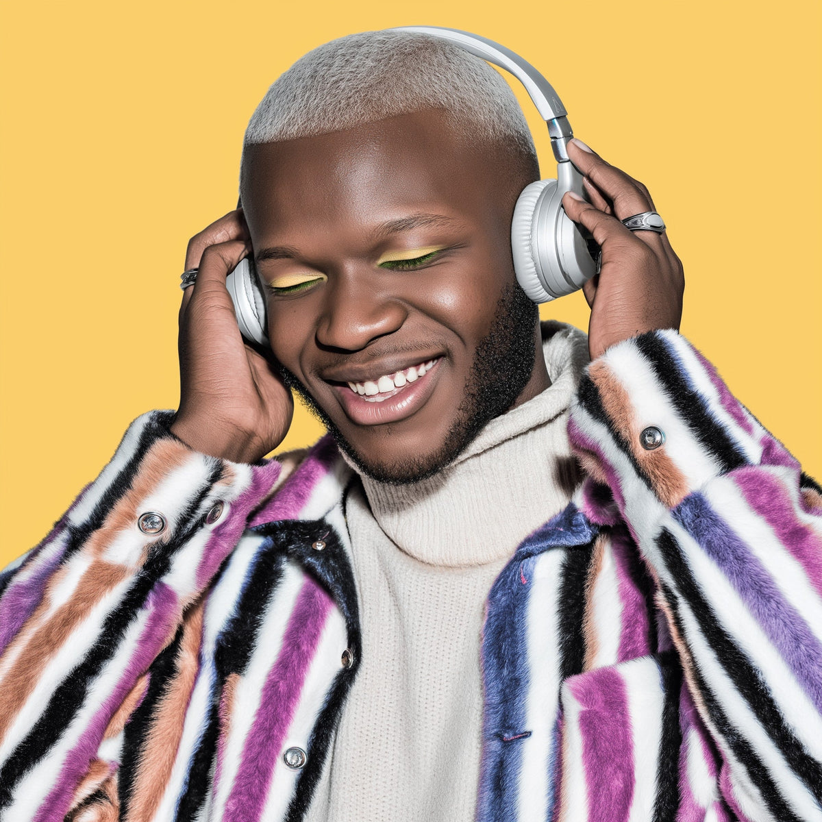 Man wearing headphones with a colorful striped coat on a yellow background