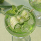 Green cocktail with cucumber slices and mint leaves in a glass.