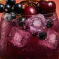 Glass of purple drink with ice and berries on a red background