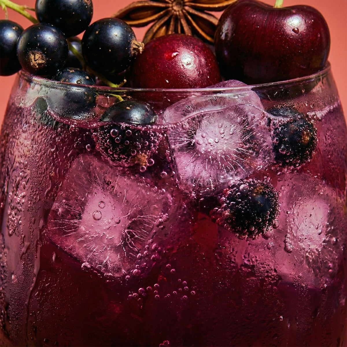 Glass of purple drink with ice and berries on a red background
