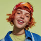 Person with red hair and colorful headband against a green background